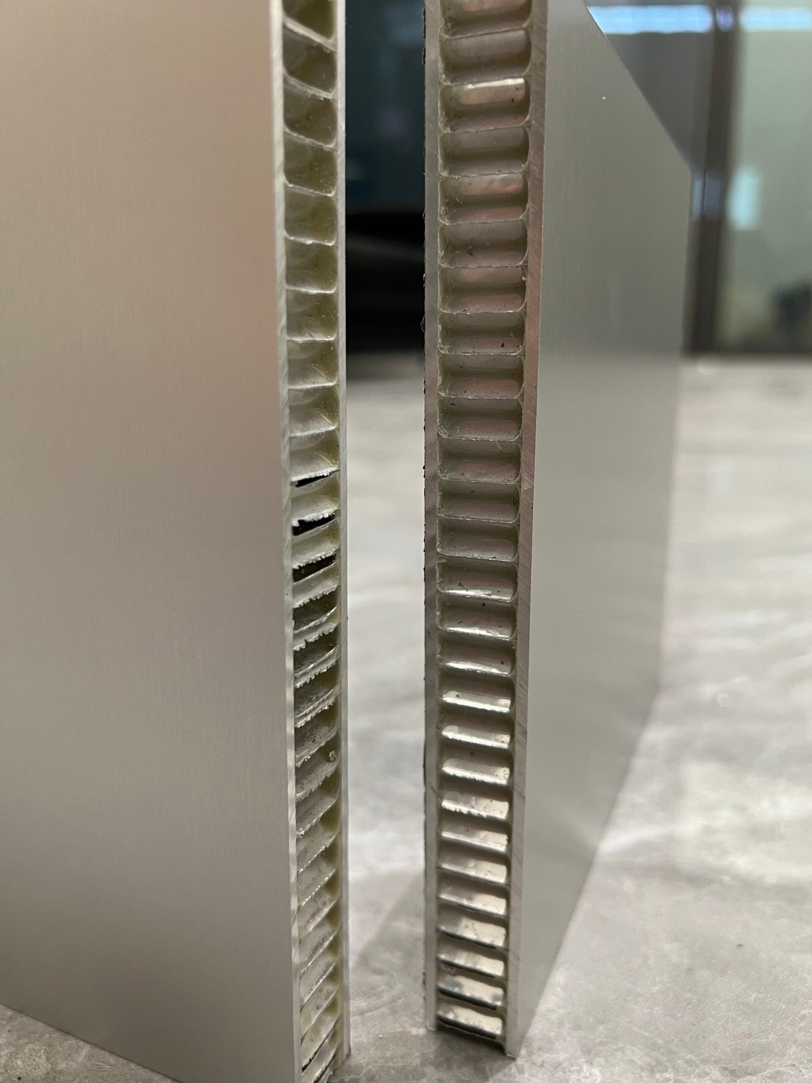 Two aluminum honeycomb panels stood on edge, comparing an opened edge with a sealed one