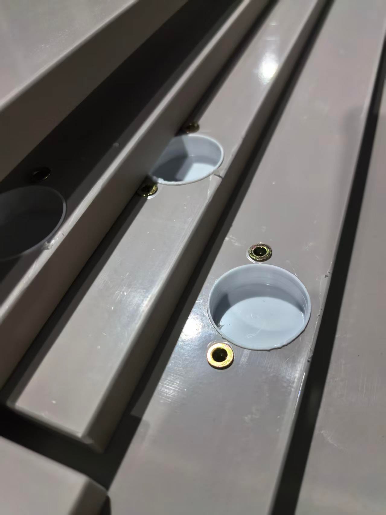 Hinge cup holes and threaded brass inserts machined into gray aluminum cabinet door panels