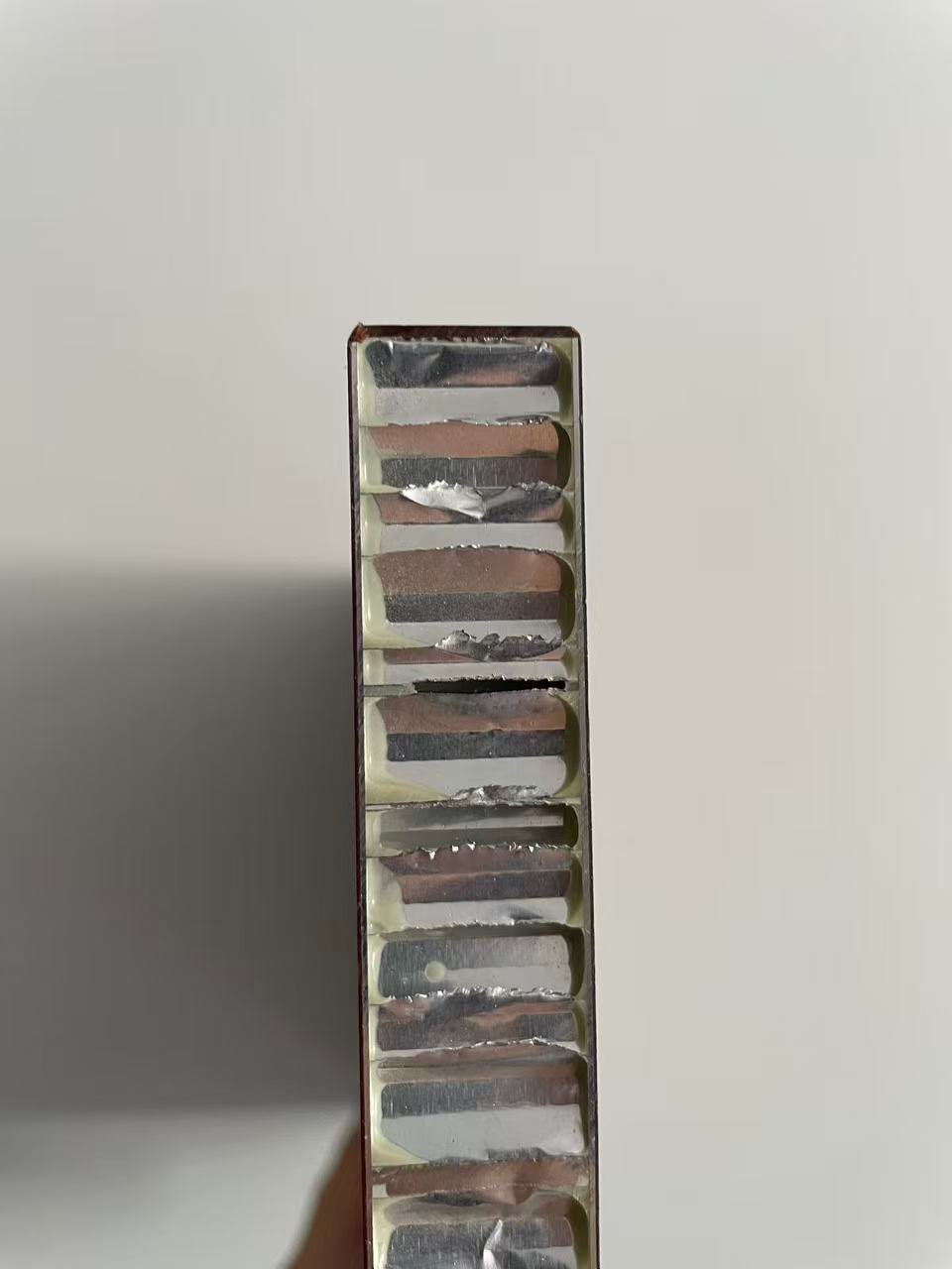 A close-up of an opened aluminum honeycomb panel edge with the core cells exposed
