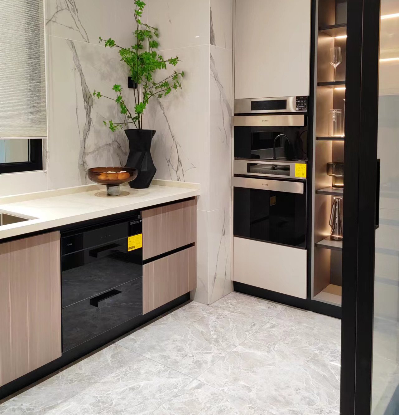 Kitchen and vanity scene with aluminum base cabinets, tall built-in oven units, a stone countertop, and a marble-tiled wall